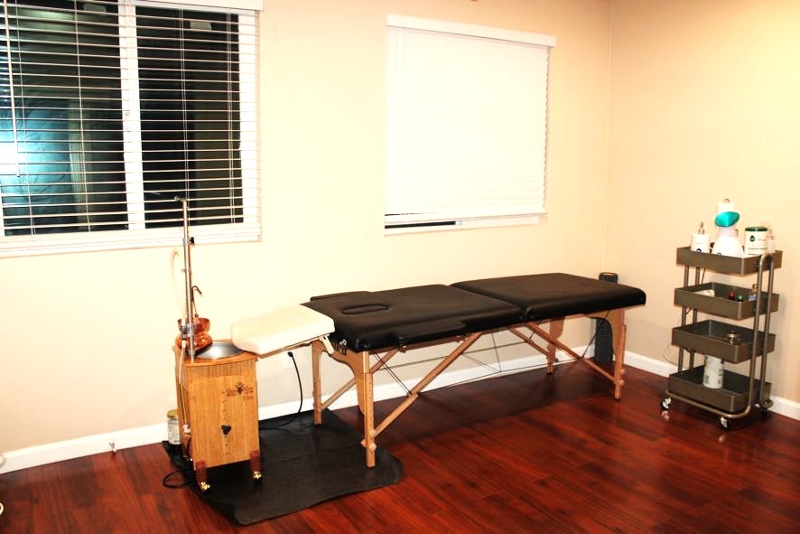 Massage table setup in a minimalistic room with wooden floors.